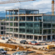 Residential house, commercial office, and industrial facility visible across a construction landscape, illustrating three major construction sectors.