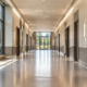 Well-lit commercial hallway with wide unobstructed circulation, accessible doors along both sides, continuous ceiling lighting, and an exit at the far end.