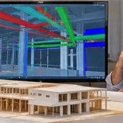 Design team studies a 3D building model and coordination view before construction to resolve a beam and service-route conflict.