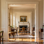 Aligned doorways frame a sequence of sunlit historic rooms, showing the enfilade layout and uninterrupted sightline through a classical home.