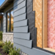 Cutaway of a house exterior wall showing siding, a weather barrier, sheathing, insulated timber framing, and interior finish.