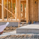 Inspector and residential designer review plans at a framed home with a step-free entrance, illustrating housing construction compliance checks.