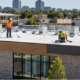 Crews inspect the broad flat roof of a low-rise building, illustrating horizontally oriented flat-roof construction.