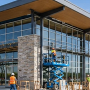 Crew installs storefront glazing and exterior cladding on a broad grocery-store building with a covered entrance canopy.