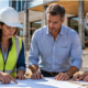 Construction professionals review plans with a client beside a modern building project, representing a general construction company’s planning and delivery work.