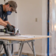 Contractor uses a dust extractor and sealed plastic doorway barrier to keep drywall renovation dust out of the occupied home.