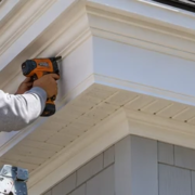 Craftsman installs projecting cornice trim where the roof eave meets the exterior wall, showing fascia, soffit, and weather-protective detailing.