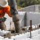 Construction crew pours concrete into insulated form blocks around reinforcing bars to create an ICF wall.