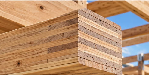 Layered veneer plies are visible at the cut end of an engineered laminated veneer lumber beam within a wood-framed building.