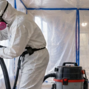 Renovation crew works inside plastic containment using respirators and HEPA extraction as part of lead-safe practice.
