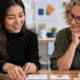 Educator and instructional designer arrange architecture course materials beside a building model and laptop, illustrating learning-content design.