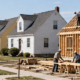 Postwar Levittown-style street shows standardized detached homes and one house still being built, illustrating mass housing construction.