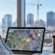 Project manager checks a city map and nearby building projects from an office overlooking active commercial construction.