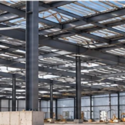 Steel frame and metal roof and wall panels form a commercial metal building under construction as a worker checks the structure.