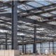 Steel frame and metal roof and wall panels form a commercial metal building under construction as a worker checks the structure.