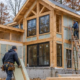 Energy-efficient timber-framed house being built in Michigan with insulation, windows, and crews working in a cool autumn setting.
