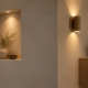 Modern interior showing a recessed wall niche and ceiling light beside a projecting wall sconce and cabinet to compare flush and protruding design features.