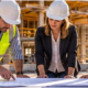 Owner, architect, and contractor review project drawings together at an active construction site.