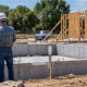 Builder and inspector review a new home foundation while framing is ready for the next step in residential construction.