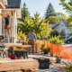 Residential construction crew works in morning daylight behind safety barriers beside neighboring homes.