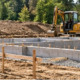 Site engineer surveys graded soil and fill around a staked residential foundation area before construction.