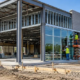 Construction team installs a glass storefront on the steel frame of a retail building.