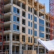 Typical mid-rise office and apartment building under construction with an engineer reviewing structural drawings on site.