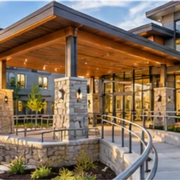 Modern senior living residence with an accessible ramp, handrails, broad windows, and a landscaped courtyard.