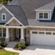 A detached single-family house stands on its own lot with a yard and driveway separated from nearby homes.