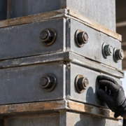 Engineer inspects a bolted steel column splice where stacked vertical structural members align across building levels.