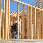Carpenters assemble dimensional lumber studs and roof trusses on site for a traditional stick-built house.