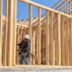 Carpenters assemble dimensional lumber studs and roof trusses on site for a traditional stick-built house.
