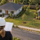 Two detached houses share one surveyed parcel while an architect and surveyor review a site plan.