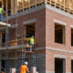 Type III construction site with masonry exterior walls and timber-framed upper structure under scaffold.