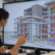 Design team reviews a 3D building model on screen to coordinate design and construction before site work.