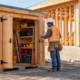 Timber dog house tool shed protecting construction equipment beside a home under construction