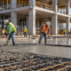 Workers pour and finish a reinforced concrete slab on a commercial building site.